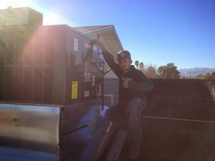 HVAC technician performing Air Duct Cleaning on a rooftop unit in Brookville